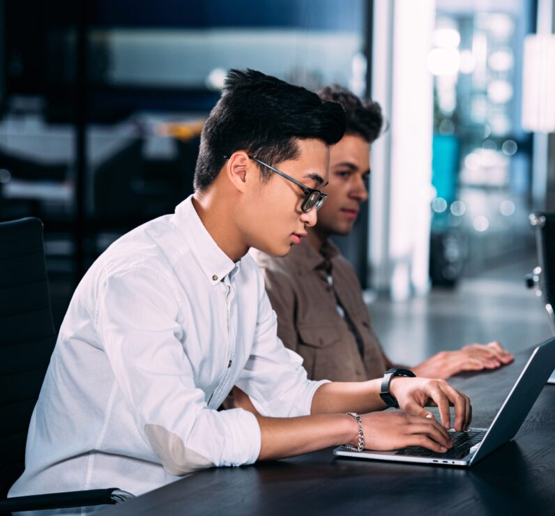 side view of multicultural businessmen working at table with laptops at modern office